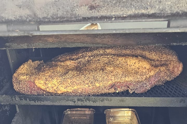 Inside the smoker, meat and pans on the rack