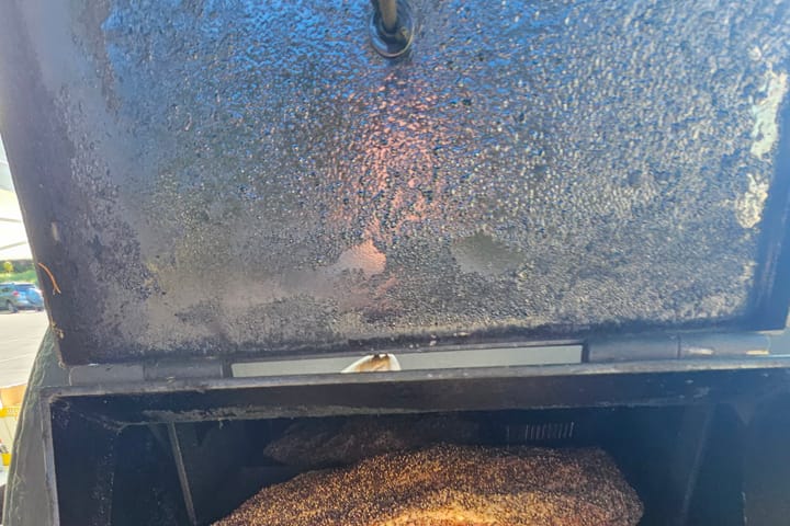 Inside the smoker, meat and pans on the rack
