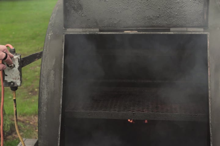 Smoke rolling out of the open smoker