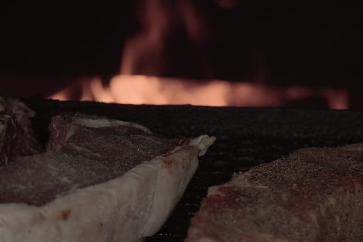 A steak on the grate with flame behind it