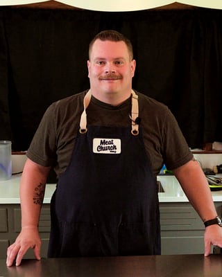 Joel in the kitchen, apron on, smiling
