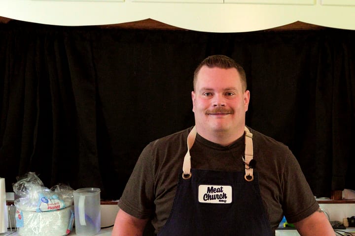 Joel in the kitchen, apron on, smiling